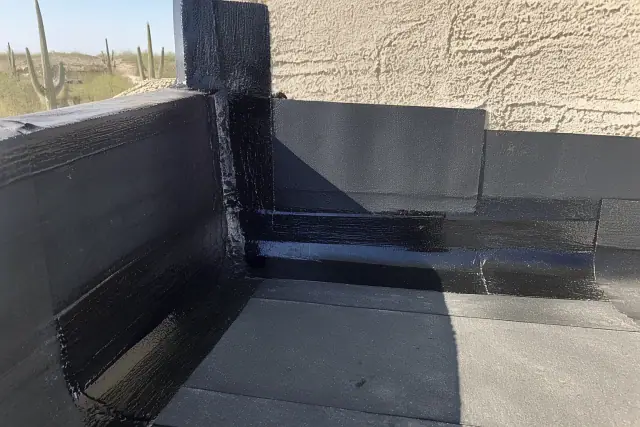 Close-up of bitumen-saturated roofing layers and sealed joints on a parapet wall in Peoria, AZ.