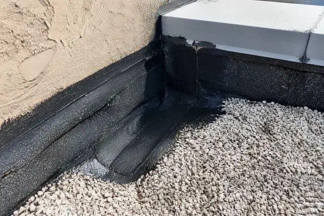 Close-up of a commercial flat roof repair on a parapet wall with sealant and gravel ballast in Phoenix, AZ.