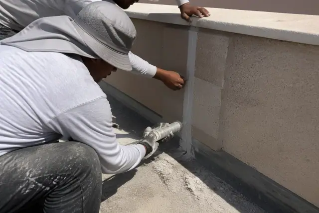 Contractor sealing joints on a commercial roof parapet wall in Phoenix, AZ.