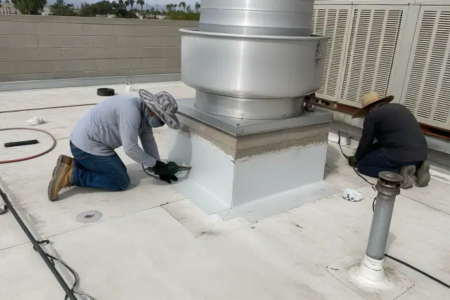 Technicians repairing a flat roof with heat-welded TPO membrane around a ventilation unit in Gilbert, AZ.