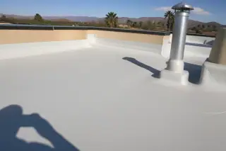 Finished commercial flat roof repair with tan gravel ballast and desert mountains in the background in Phoenix, AZ.