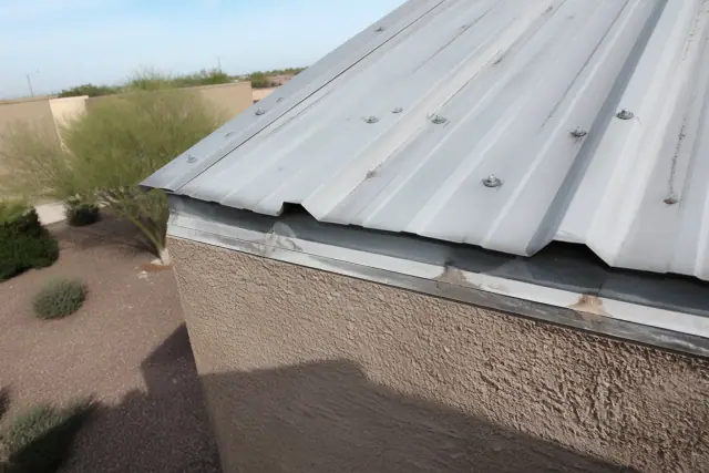 Close-up of overlapping metal roofing panels with industrial screws on a commercial building in Surprise, AZ.