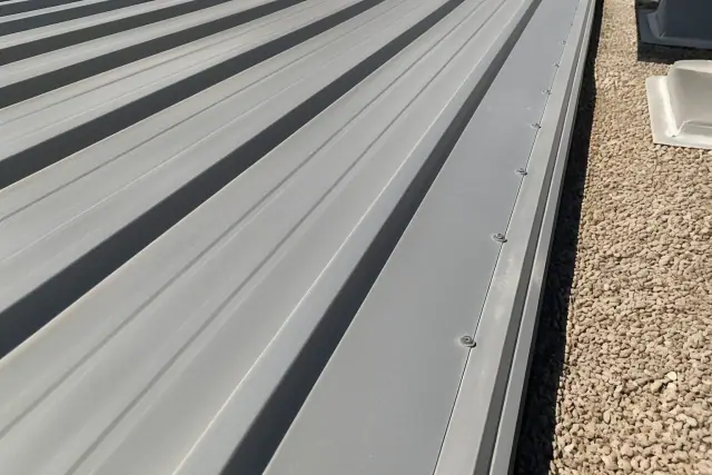 Industrial screws securing overlapping metal roof panels on a commercial building in Phoenix, AZ.