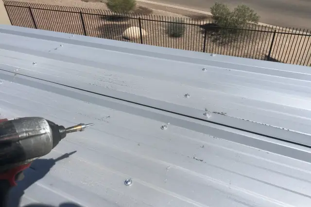 Industrial screws securing metal roofing panels on a commercial building in Peoria, AZ.