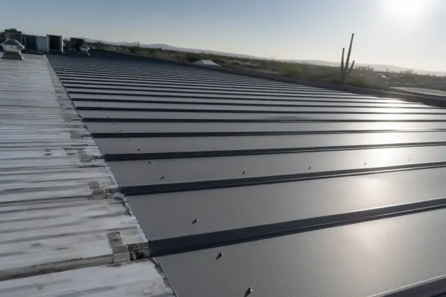 Close-up of overlapping metal roofing sheets secured with fasteners on a commercial building in Phoenix, AZ.