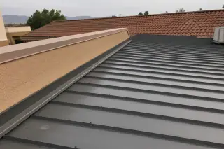 Metal roofing panels with industrial screws near a stucco parapet and red-clay tile roof in Phoenix, AZ.
