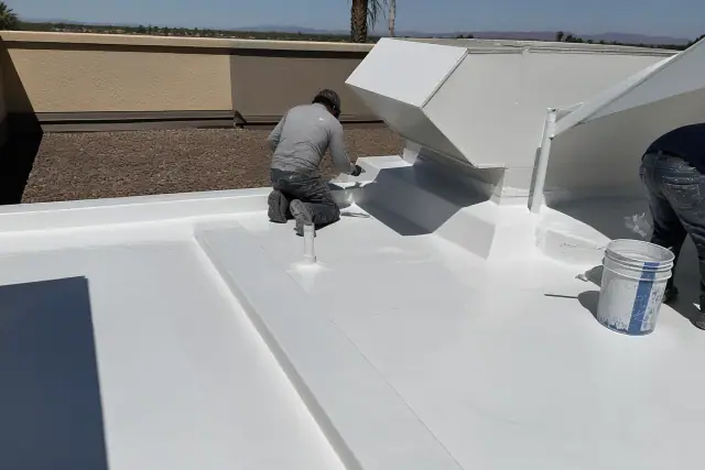 Contractor applying a smooth white liquid roof coating to membrane seams on a commercial rooftop in Buckeye, AZ.
