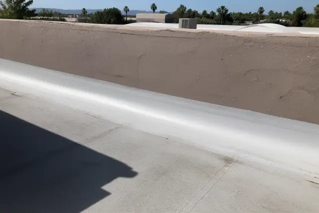 Liquid membrane coating applied to a parapet wall seam on a gravel commercial roof in Phoenix, AZ.