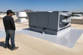 Technician observing a cured white roof coating around a ventilation unit with desert mountains in Phoenix, AZ.