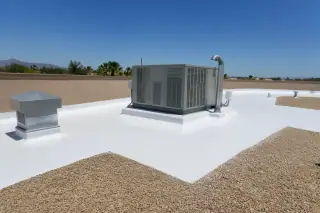 White reflective roof coating applied around a ventilation unit and stucco parapet in Phoenix, AZ.