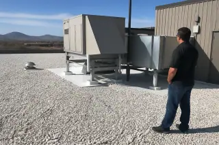 White gravel roof ballast surrounding a ventilation unit with distant desert mountains in Phoenix, AZ.