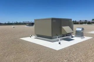 Wide view of a finished gravel roof and ventilation unit under a bright blue sky in Phoenix, AZ.