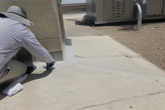 Technicians applying roofing sealant to a membrane seam on a commercial rooftop in Buckeye, AZ.