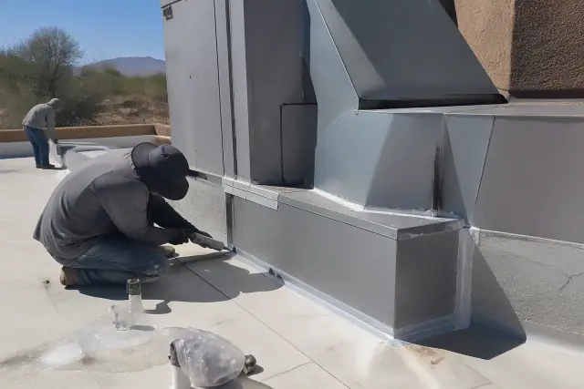 Roofing technicians applying sealant around a ventilation unit on a commercial roof in Glendale, AZ.