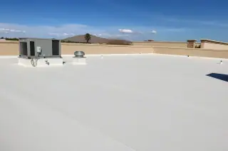 New roofing membrane with clean seams next to a tan stucco parapet and desert foothills in Phoenix, AZ.