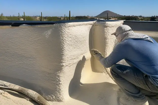 Crew members applying spray foam insulation to a roof parapet wall in Phoenix, AZ.