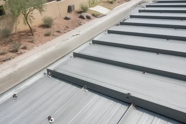 Overlapping corrugated metal roofing panels with industrial fasteners on a commercial roof in Phoenix, AZ.