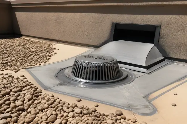 New metal debris grate installed over a roof drain on a gravel commercial roof in Phoenix, AZ.