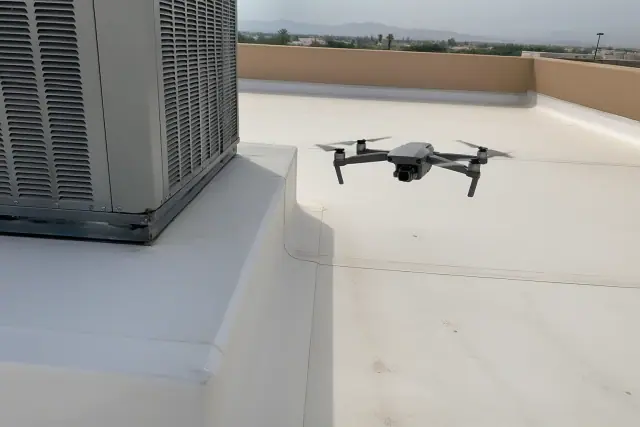 A drone inspects the seams of a commercial flat roof near an HVAC unit in Phoenix, AZ.
