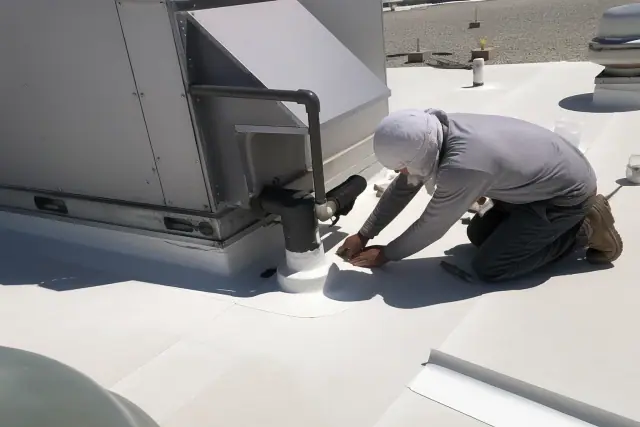 Technicians performing TPO membrane detailing on a roof near a ventilation unit in Phoenix, AZ.