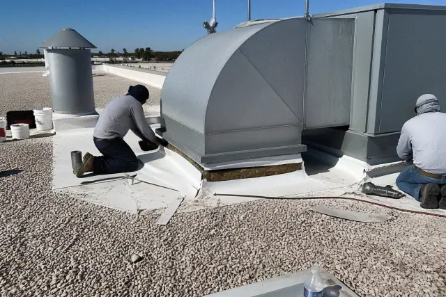 Technicians detailing a TPO membrane around an HVAC unit on a gravel roof in Phoenix, AZ.