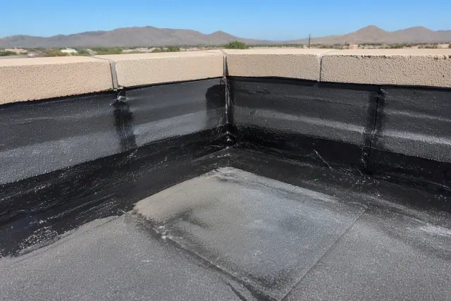 Close-up of bitumen membrane roofing being sealed along a parapet wall at a job site in Phoenix, AZ.
