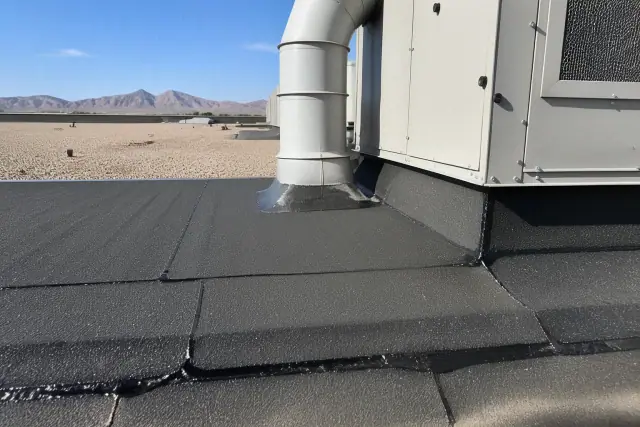 Technicians detail a modified bitumen roof around a ventilation unit in Peoria, AZ with gravel ballast and mountain views.