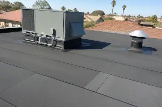 Modified bitumen roofing with seamless flashing around a ventilation unit near terracotta tiles in Phoenix, AZ.