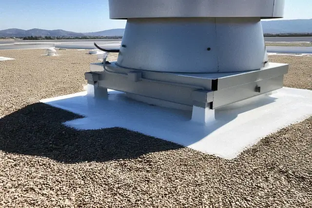 Fresh white reflective roof coating applied around metal equipment on a commercial rooftop in Phoenix, AZ.