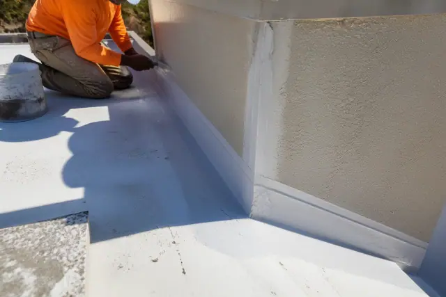 Contractor sealing a commercial flat roof parapet joint in Phoenix, AZ.