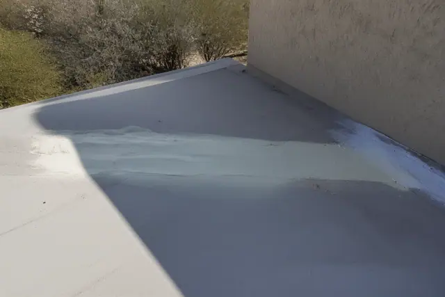 Technician repairing a wide expansion joint with polyurethane foam on a roof in Phoenix, AZ.