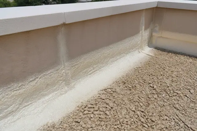 Spray foam insulation applied to a commercial parapet wall on a gravel roof in Glendale, AZ.