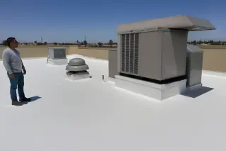 White spray foam roof with a rooftop HVAC unit and tan stucco parapet in Phoenix, AZ.