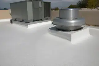 Seamless spray foam roofing around a rooftop HVAC unit with a tan stucco parapet in Phoenix, AZ.