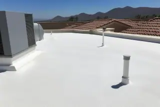 Seamless white spray foam roofing finish with sun-bleached terracotta tiles and desert mountains in Phoenix, AZ.