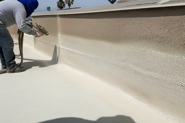 Contractors applying spray polyurethane foam to a commercial flat roof parapet wall in Phoenix, AZ.