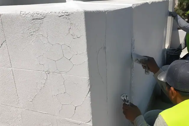 Contractors applying new elastomeric coating to a cracked stucco parapet wall on a building in Phoenix, AZ.