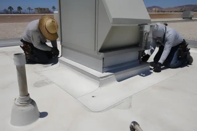 Technicians inspecting a TPO membrane seam around a rooftop HVAC unit on a commercial building in Phoenix, AZ.