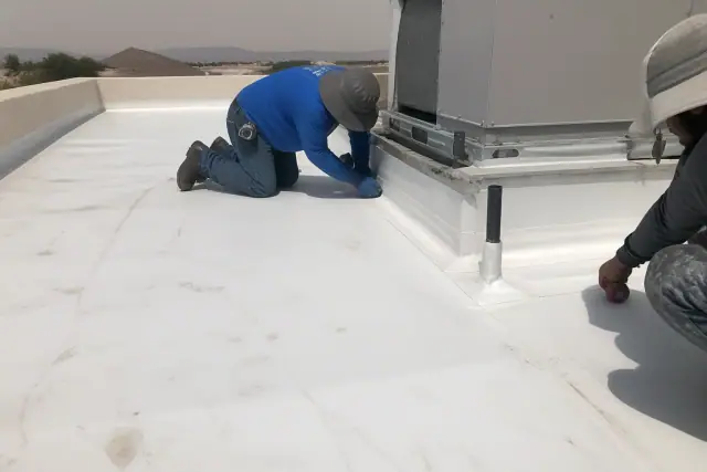 Technicians heat-welding TPO roofing membrane seams near a ventilation unit on a rooftop in Phoenix, AZ.