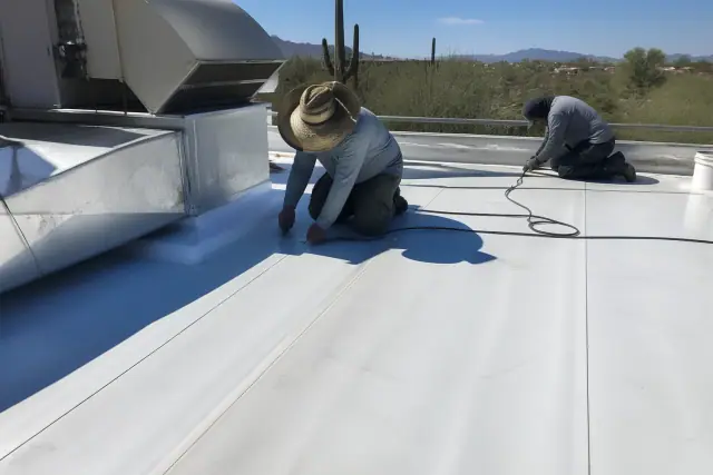 Technicians installing a white TPO roofing membrane around a rooftop ventilation unit in Scottsdale, AZ.