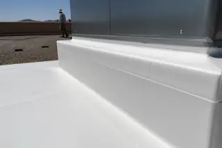 Heat-welded TPO membrane seams and stucco parapet wall on a flat roof in Phoenix, AZ.
