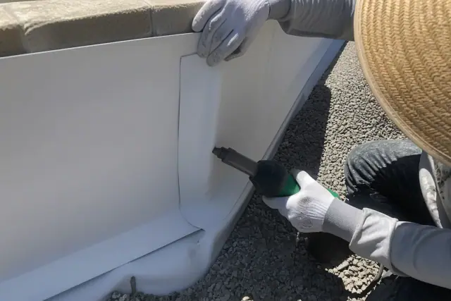 Crew members performing TPO seam welding and parapet flashing on a gravel roof in Phoenix, AZ.