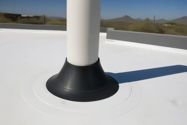 TPO roofing membrane with a heat-welded rubber pipe boot at a job site in Phoenix, AZ, with distant desert saguaros.