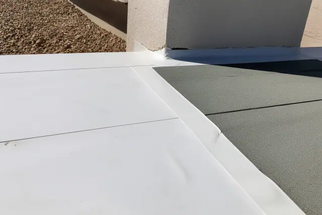 White TPO roofing membrane and granulated base sheet overlapping on a flat roof in Phoenix, AZ.