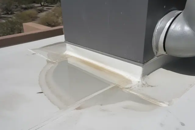 Standing water on a white TPO roof membrane near a ventilation unit at a job site in Phoenix, AZ.