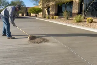 Worker sweeping construction dust from a cured concrete surface in Phoenix, AZ.