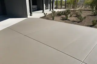 Finished commercial concrete slab with expansion joints and prickly pear cacti in the midday sun in Phoenix, AZ.