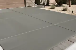 Cured concrete driveway with a subtle textured surface next to a stucco house in Phoenix, AZ.