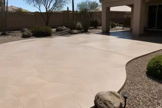 Smooth concrete patio with a decorative stone texture and desert landscaping in a backyard in Phoenix, AZ.