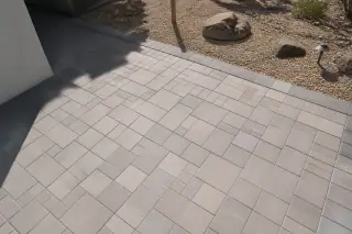 Interlocking concrete pavers with sand-filled joints and finished edges in a Phoenix, AZ backyard with desert gravel.